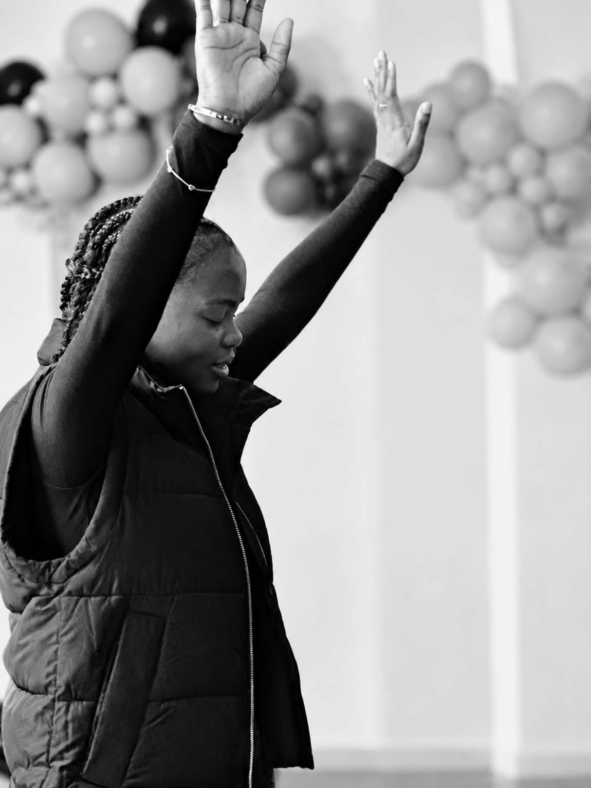 A young woman worshipping with both hands raised at Revive City Church