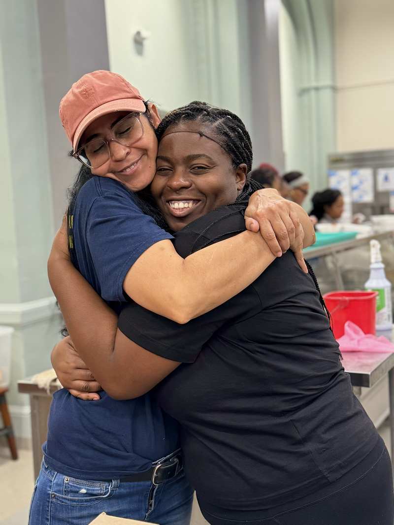 Two volunteers embracing while serving a community meal