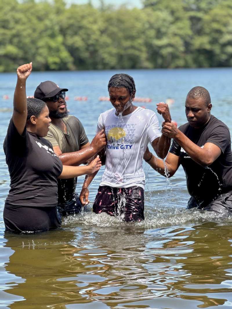 A young man being baptized in a lake by Revive City pastors