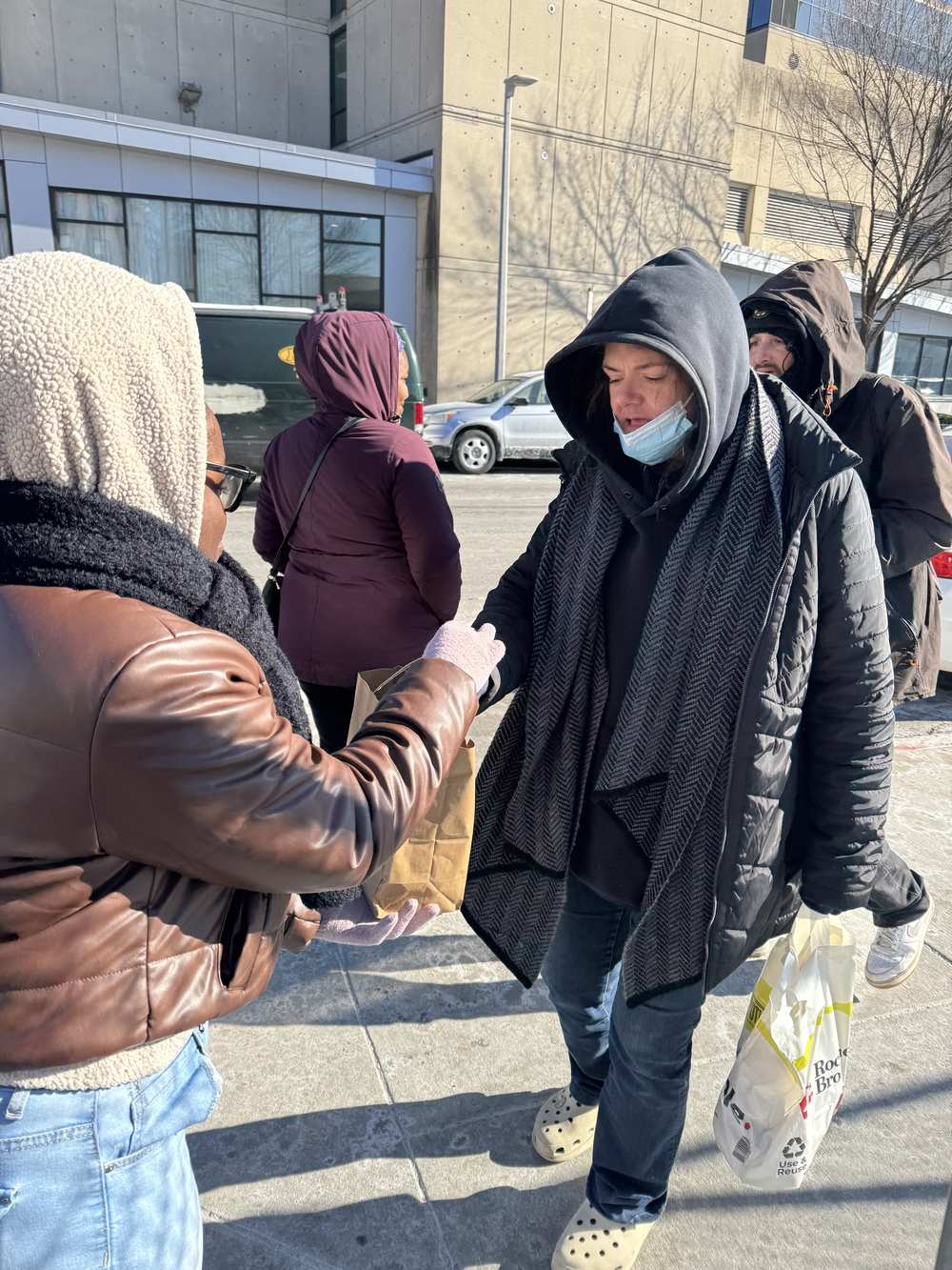 A Revive City volunteer handing a meal to a neighbour on a winter morning in Boston